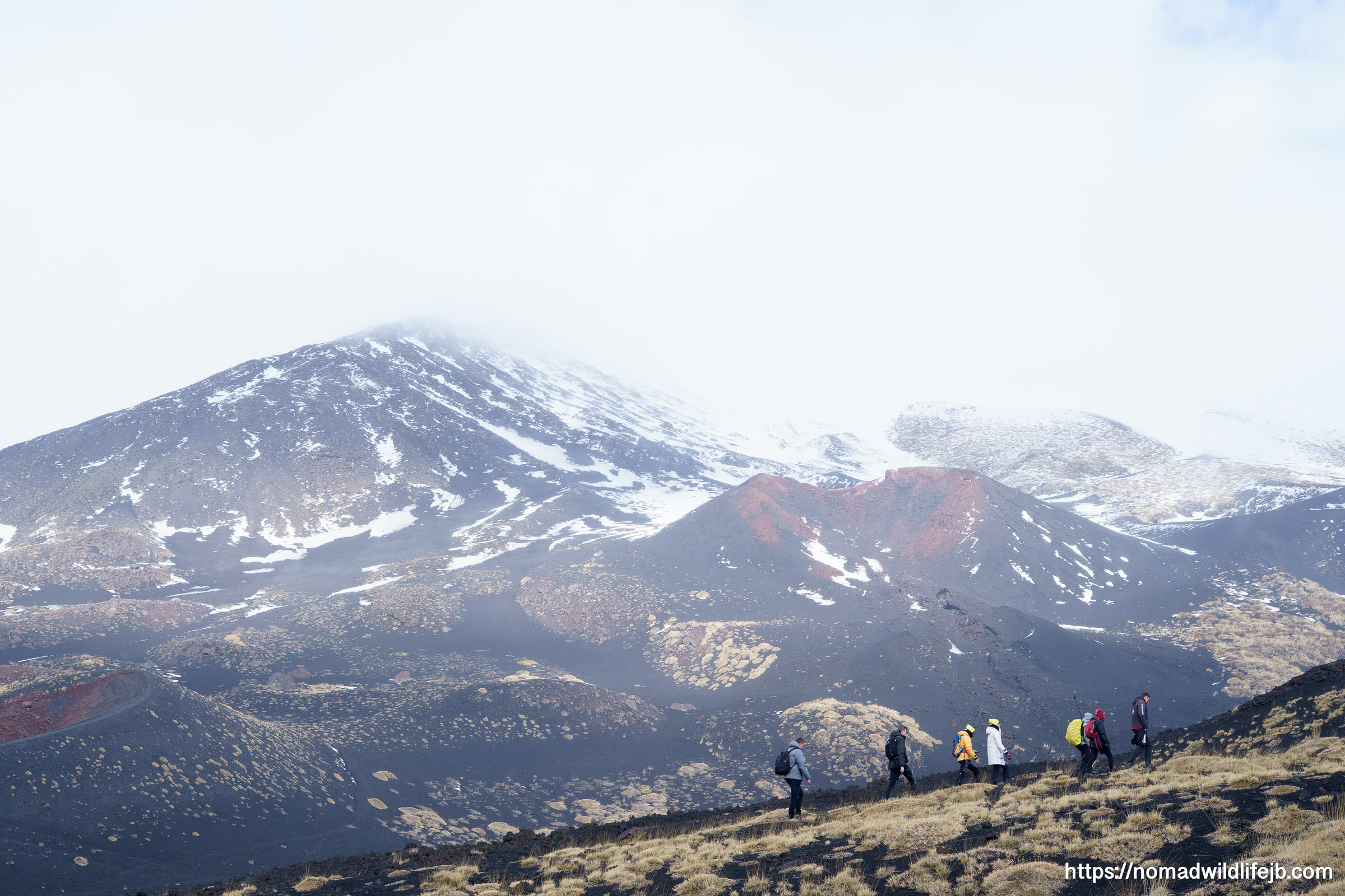 Snow and black volcanic sand meeting on the slopes of Mount Etna under heavy fog