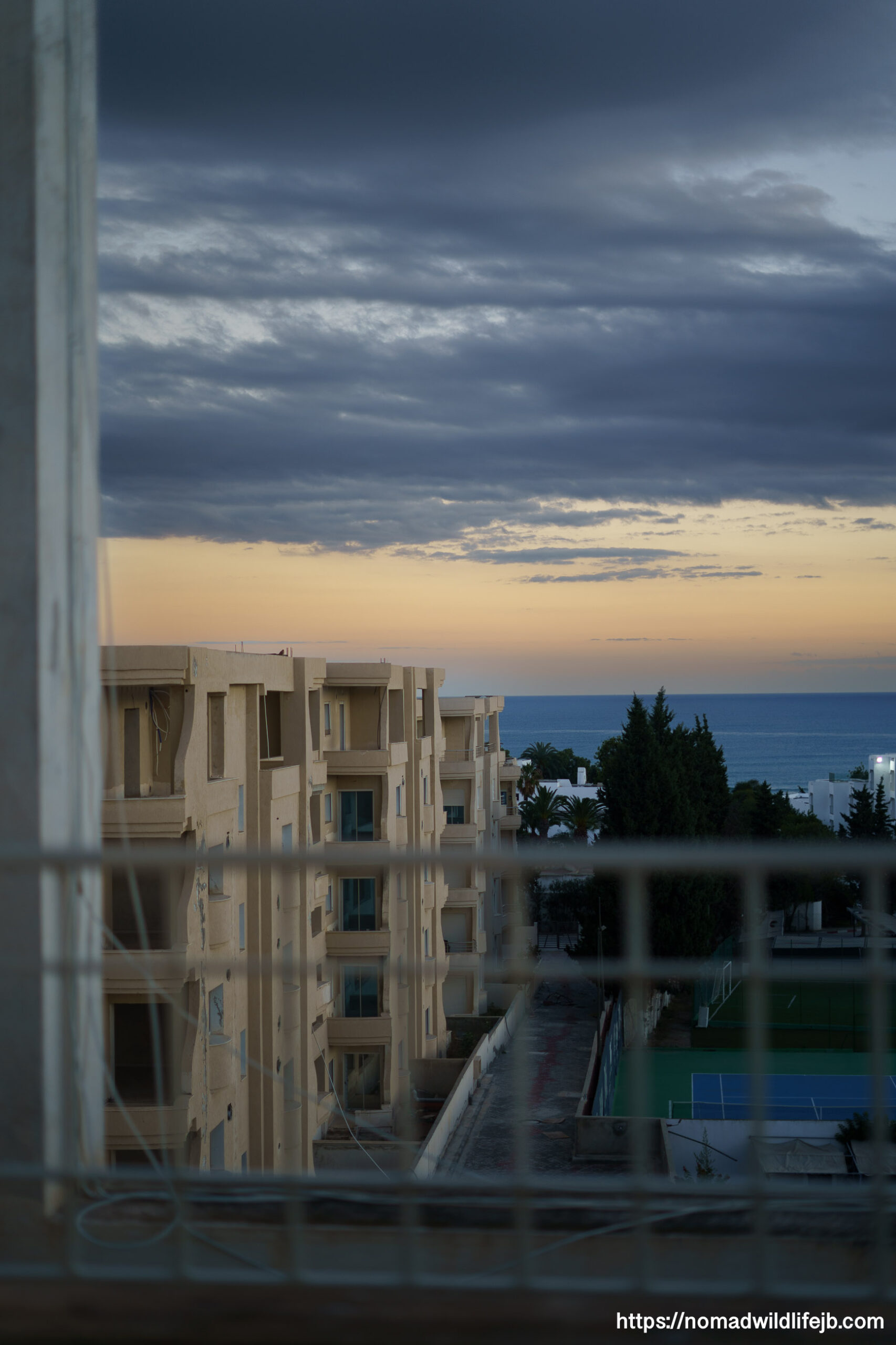 Apartment buildings and a walkway leading toward the Mediterranean Sea in Hammamet, Tunisia at sunset