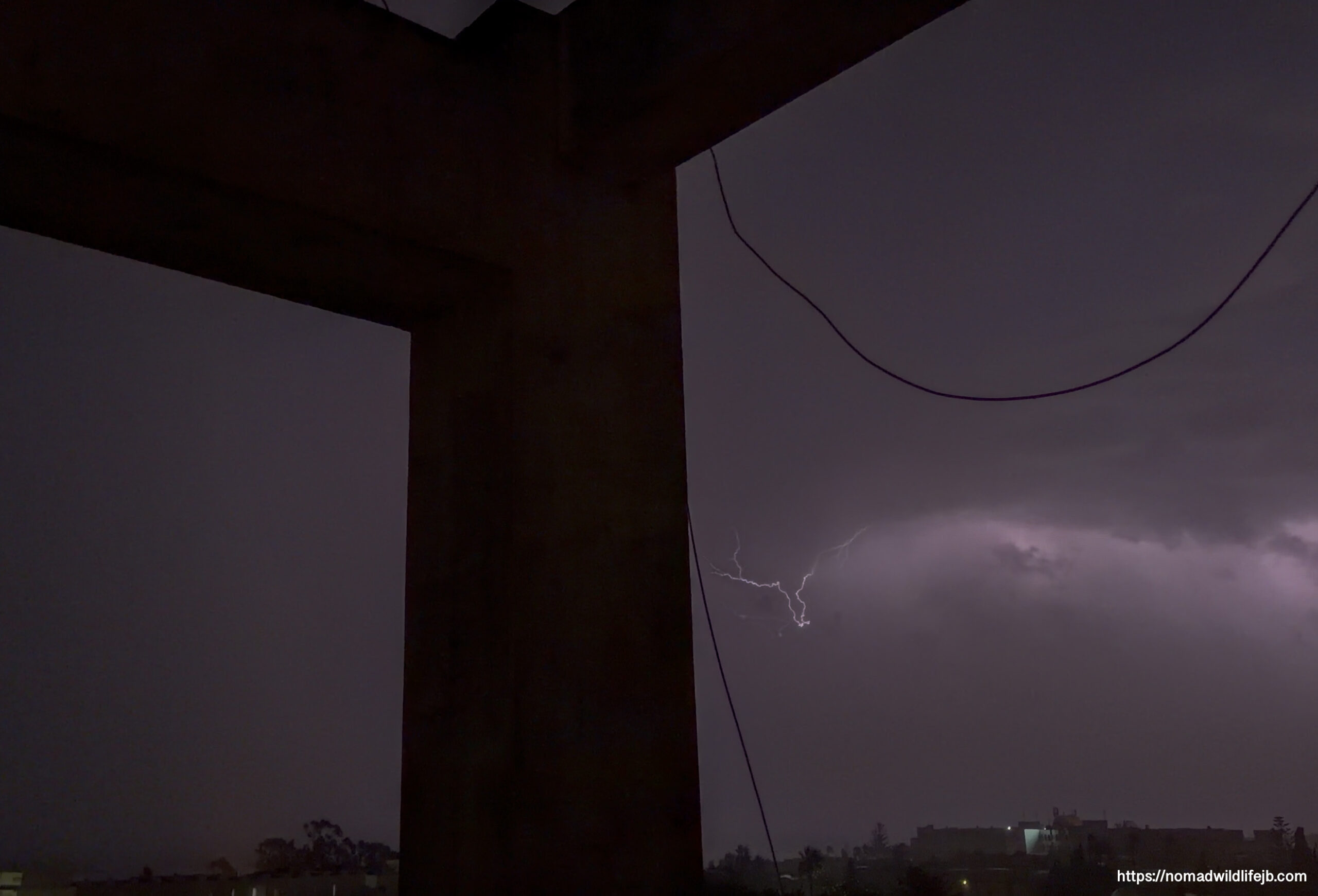 Lightning branching beneath storm clouds above Hammamet, Tunisia, framed by concrete columns