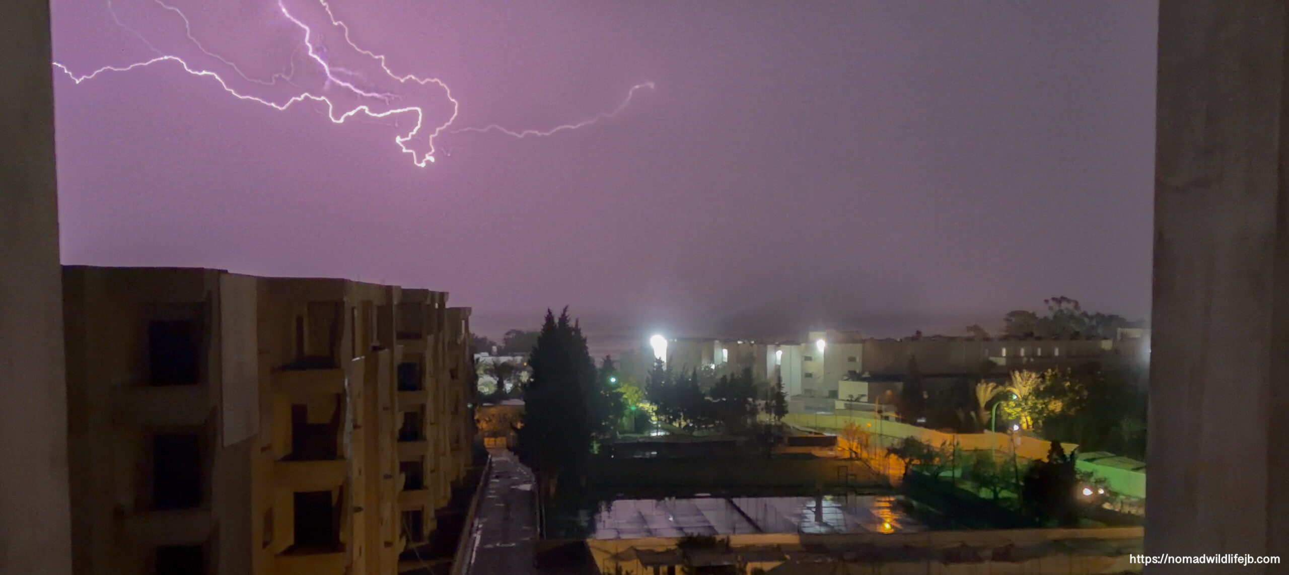 Lightning illuminating rain-soaked streets and buildings at night in Hammamet