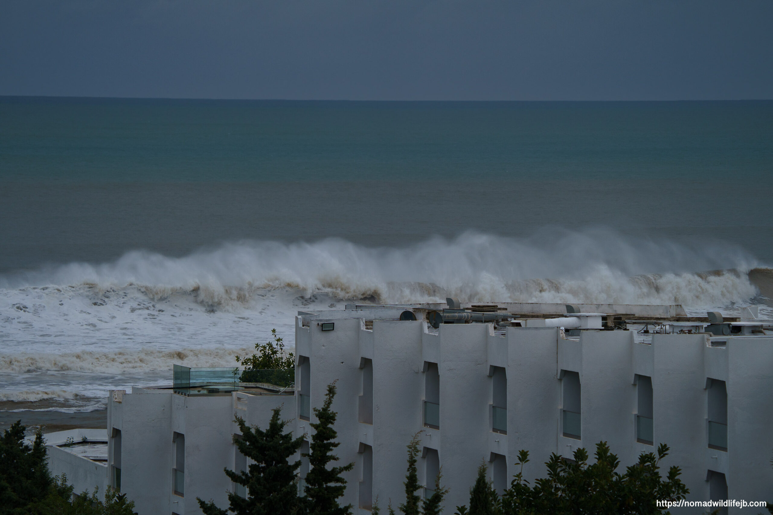 Storm surf breaking behind white rooftops along the coast in Hammamet, Tunisia.