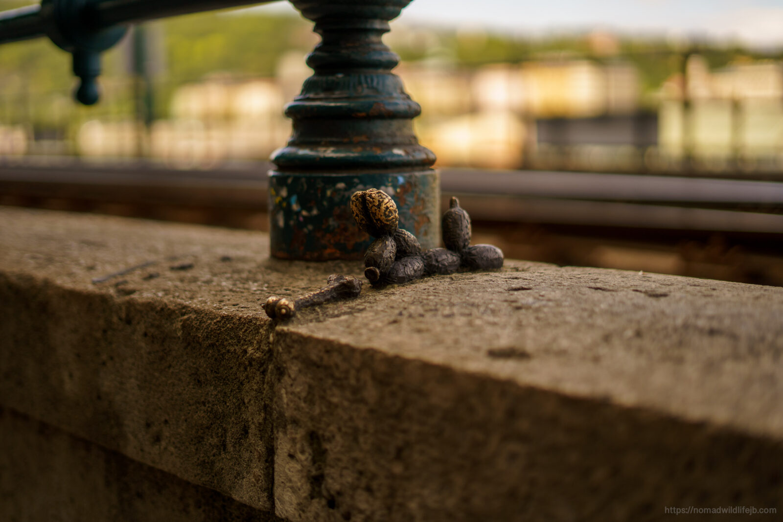 Tiny bronze balloon dog sculpture resting beside a lamppost along the Danube riverfront in Budapest.